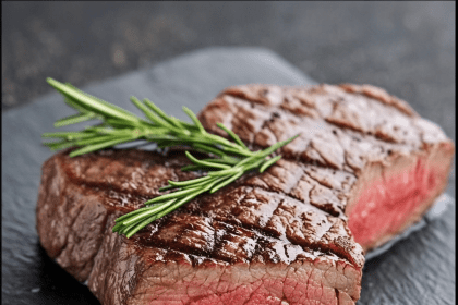 Juicy grilled steak with rosemary on a black slate, representing tips on how to soften tough cooked meat effectively