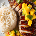 Juicy tamarind-ginger pork tenderloin served with fluffy coconut rice and fresh mango salsa, garnished with cilantro and lime wedges – a flavorful tropical dinner recipe